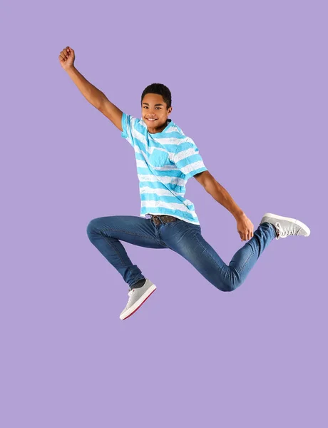 Jumping African-American teenager boy on color background — Stock Photo, Image