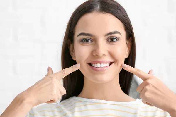 Mulher bonita com dentes saudáveis no fundo claro — Fotografia de Stock