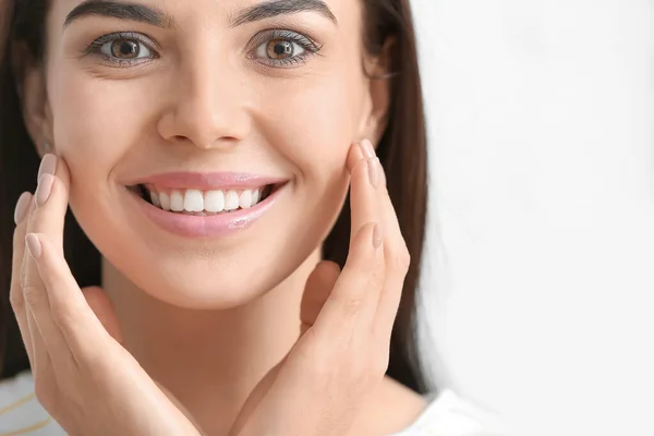 Mooie jonge vrouw met gezonde tanden op lichte achtergrond — Stockfoto