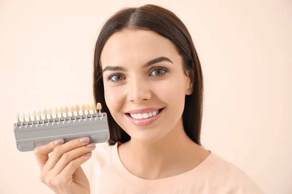 stock image Beautiful young woman with teeth color samples on light background