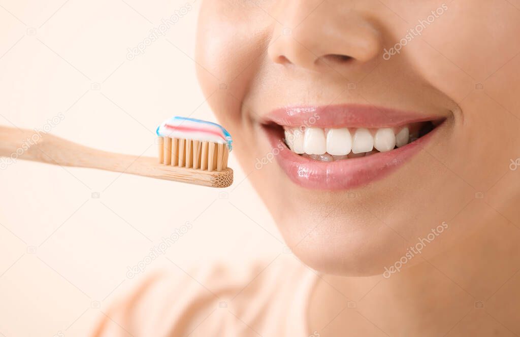 Beautiful young woman with tooth brush on light background, closeup