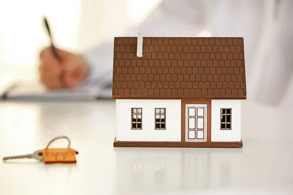 Model of house and key on table of real estate agent. Concept of buying new property — Stock Photo, Image