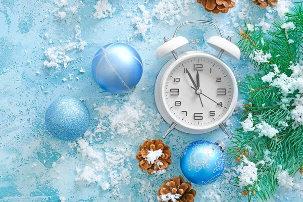Wekker klok, sneeuw en decor op kleur achtergrond. Kerst countdown concept — Stockfoto