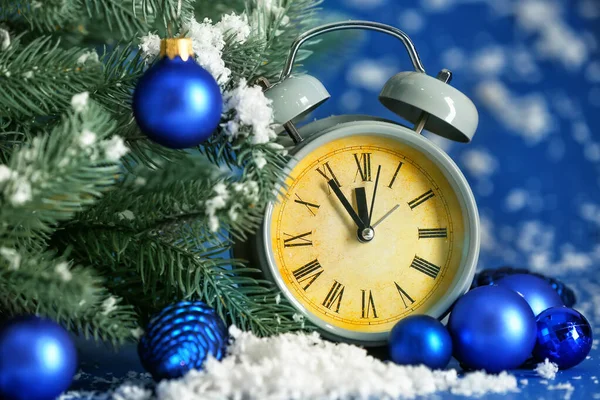 Wekker klok, dennenboom en sneeuw op kleur achtergrond. Kerst countdown concept — Stockfoto