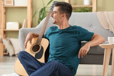 Evde gitar çalan yakışıklı bir adam.