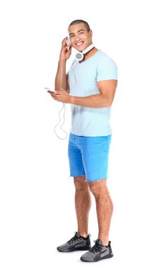 Beyaz arka planda müzik dinleyen yakışıklı bir gencin portresi.