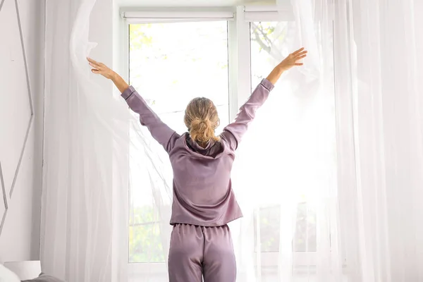 Morning of beautiful young woman opening curtains in bedroom — Stock Photo, Image