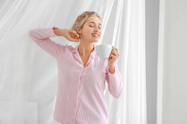 Ochtend van mooie jonge vrouw met kop koffie in de buurt van venster — Stockfoto