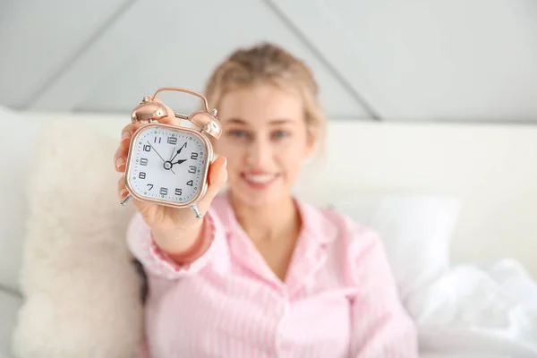 Morgen der schönen jungen Frau mit Wecker im Bett — Stockfoto