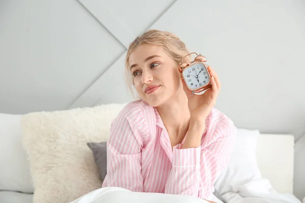 Morning of beautiful young woman with alarm clock in bed — Stock Photo, Image