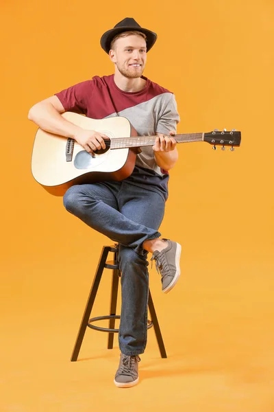Handsome man playing guitar on color background — Stock Photo, Image