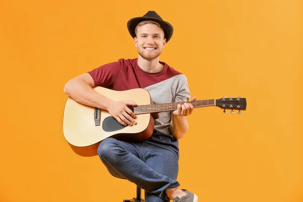 Handsome man playing guitar on color background — Stock Photo, Image