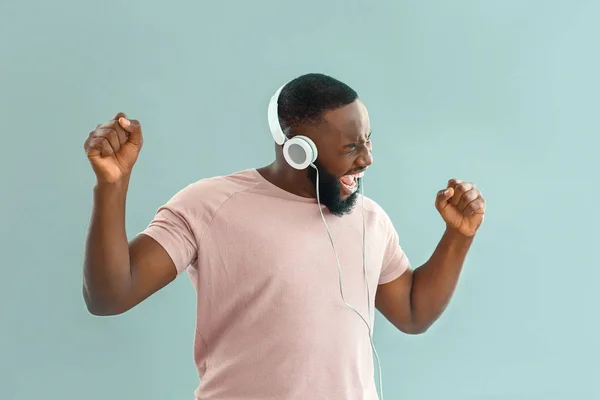 Emotional African-American man listening to music on color background — Stock Photo, Image