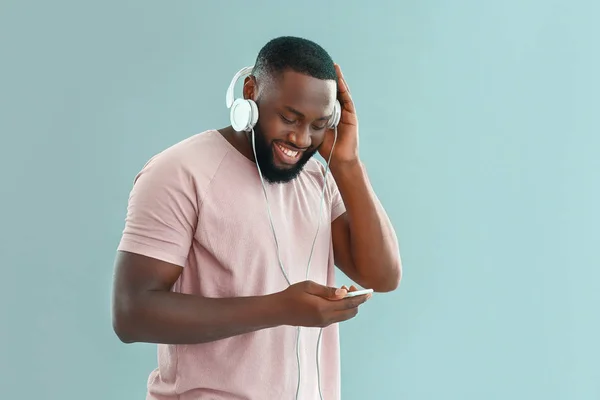 African-American man listening to music on color background — Stock Photo, Image