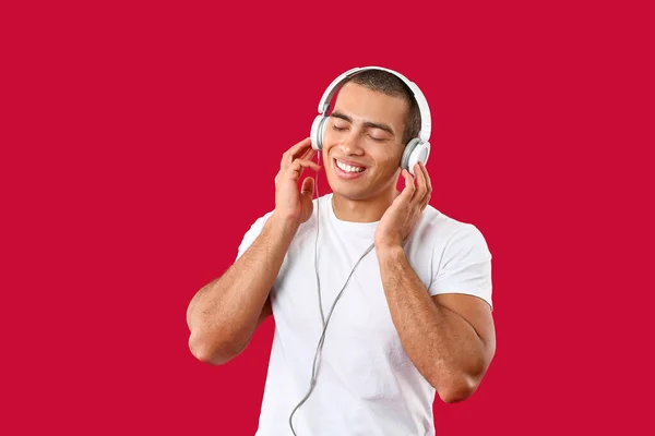 Retrato de belo jovem ouvindo música sobre fundo de cor — Fotografia de Stock