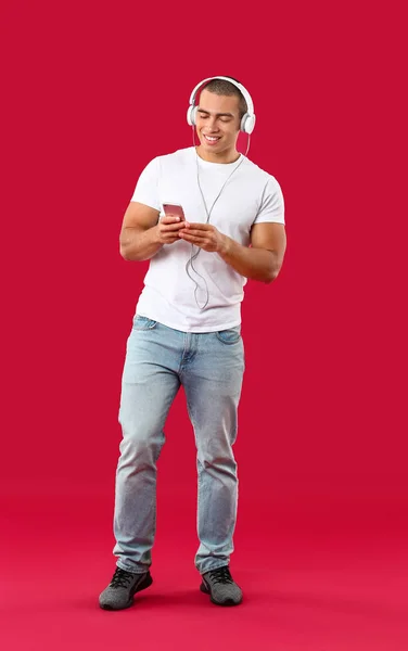 Retrato de un joven guapo escuchando música sobre fondo de color —  Fotos de Stock