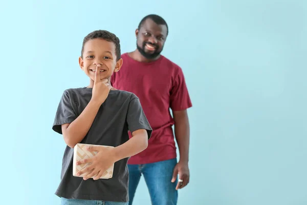 Portrait of little African-American boy with gift for his father on color background — Stock Photo, Image