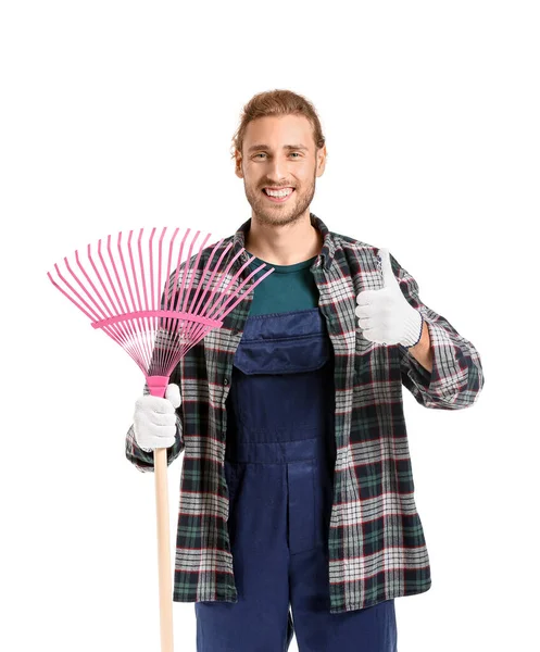 Hombre con rastrillo para las hojas de otoño de limpieza que muestra el pulgar hacia arriba sobre fondo blanco — Foto de Stock