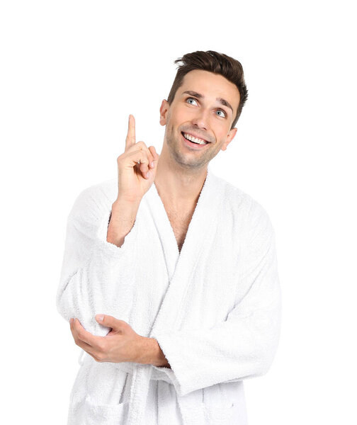 Handsome man in bathrobe pointing at something on white background