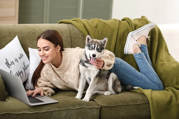 Young woman with funny husky puppy and laptop resting at home — Stock Photo, Image