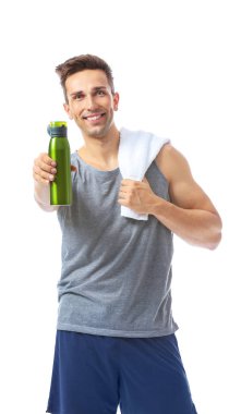 Beyaz arka planda bir şişe su ve havlusu olan sportif bir genç.