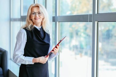 Ofisteki pencerenin yanındaki olgun iş kadınının portresi