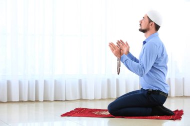 Müslüman adam odada dua ediyor.