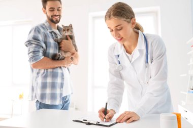 Kedisiyle birlikte veterineri klinikte ziyaret eden adam.