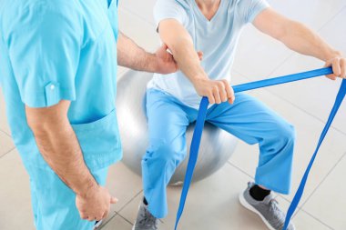 Rehabilitasyon merkezinde erkek hastayla çalışan fizyoterapist.