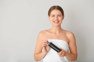 Hafif arka planda kozmetik ürünleri olan güzel genç bir kadın.