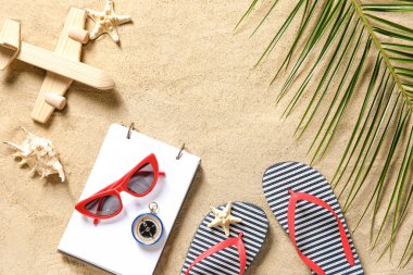 Tahta uçak ve kumda defter olan plaj aksesuarları.