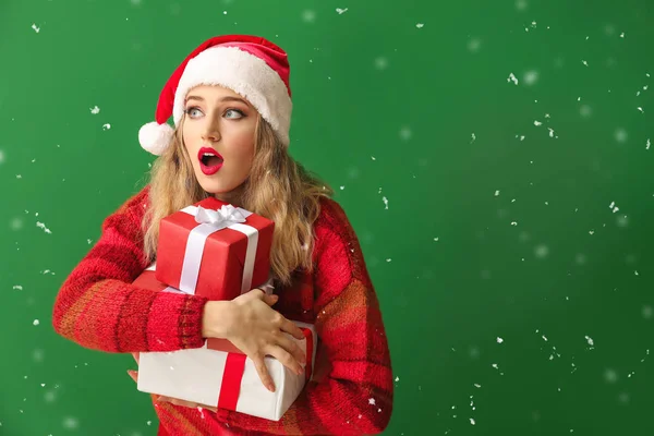驚くべき若い女性ですクリスマスプレゼントと色の背景に雪 — ストック写真