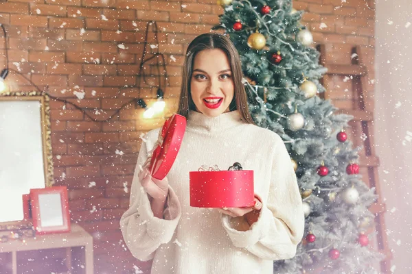 Beautiful young woman with Christmas gift at home — Stock Photo, Image