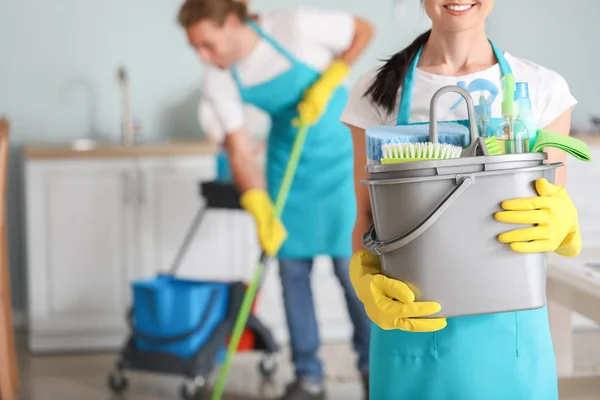 Vrouwelijke conciërge met schoonmaakmiddelen in de keuken — Stockfoto