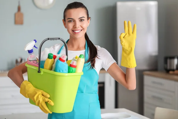 Vrouwelijke conciërge met schoonmaakmiddelen in de keuken — Stockfoto