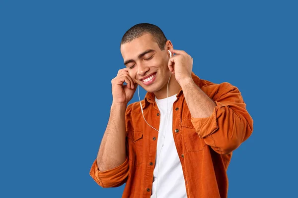 Portret van knappe jongeman luisteren naar muziek op kleur achtergrond — Stockfoto