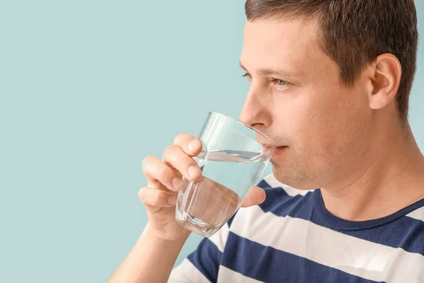 Portrait of handsome man drinking fresh water on color background — Stock Photo, Image