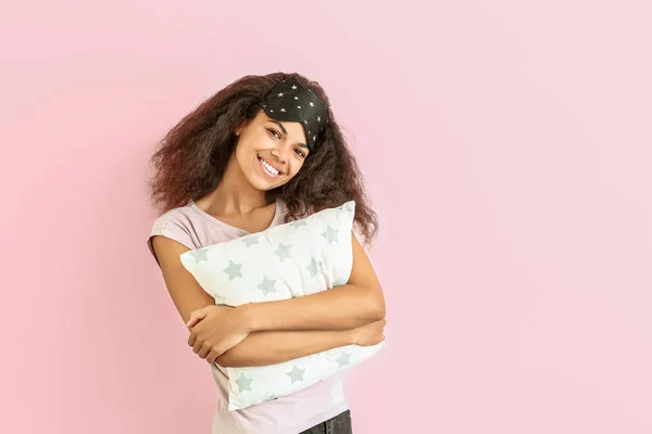 Bella donna afro-americana con maschera del sonno e cuscino su sfondo di colore — Foto Stock