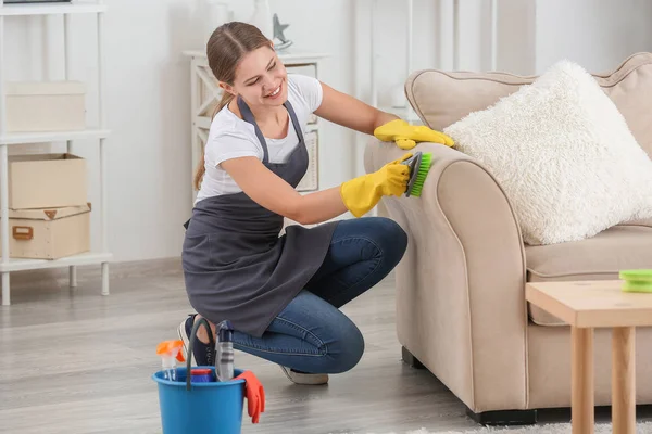 Conserje hembra limpiando muebles en la habitación — Foto de Stock