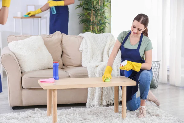 Hausmeisterin putzt Tisch im Zimmer — Stockfoto