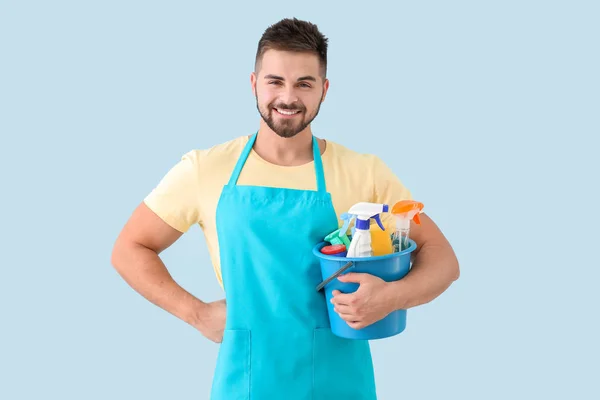 Mannelijke conciërge met schoonmaak benodigdheden op kleur achtergrond — Stockfoto