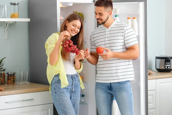 Casal jovem tirando comida da geladeira na cozinha — Fotografia de Stock