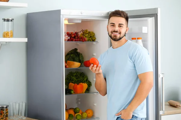 Молодий чоловік біля відкритого холодильника на кухні — стокове фото