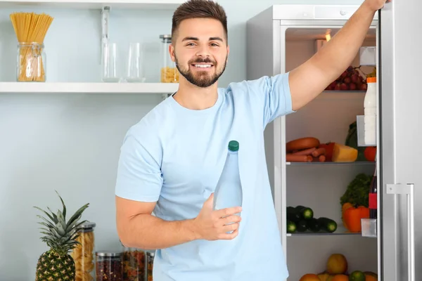 Young man near open fridge in kitchen