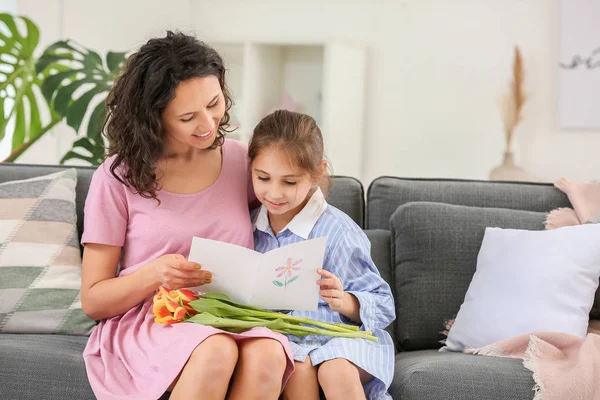 Woman with greeting card for Mother's Day and flowers received from her little daughter at home — Stock Photo, Image