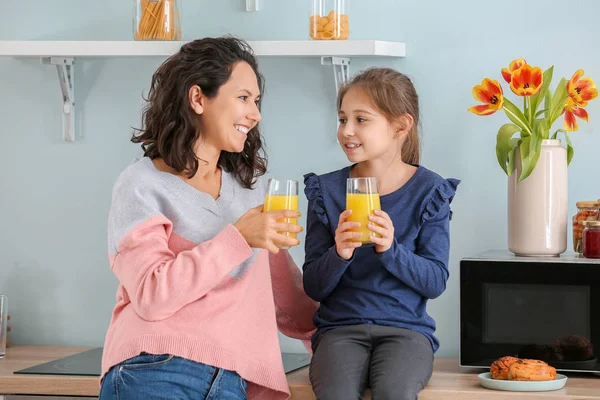 Little girl with her mother drinking juice in kitchen — Stock Photo, Image