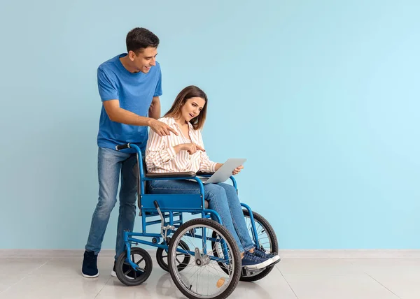带着笔记本电脑的残疾青年妇女和她的丈夫接近彩墙 — 图库照片