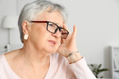 Yaşlı kadın evde baş ağrısı çekiyor.