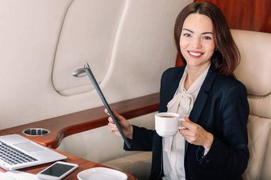Modern özel uçakta kahve içen bir iş kadını.