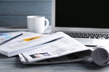Gazeteler, dizüstü bilgisayarlar ve bir fincan kahve.